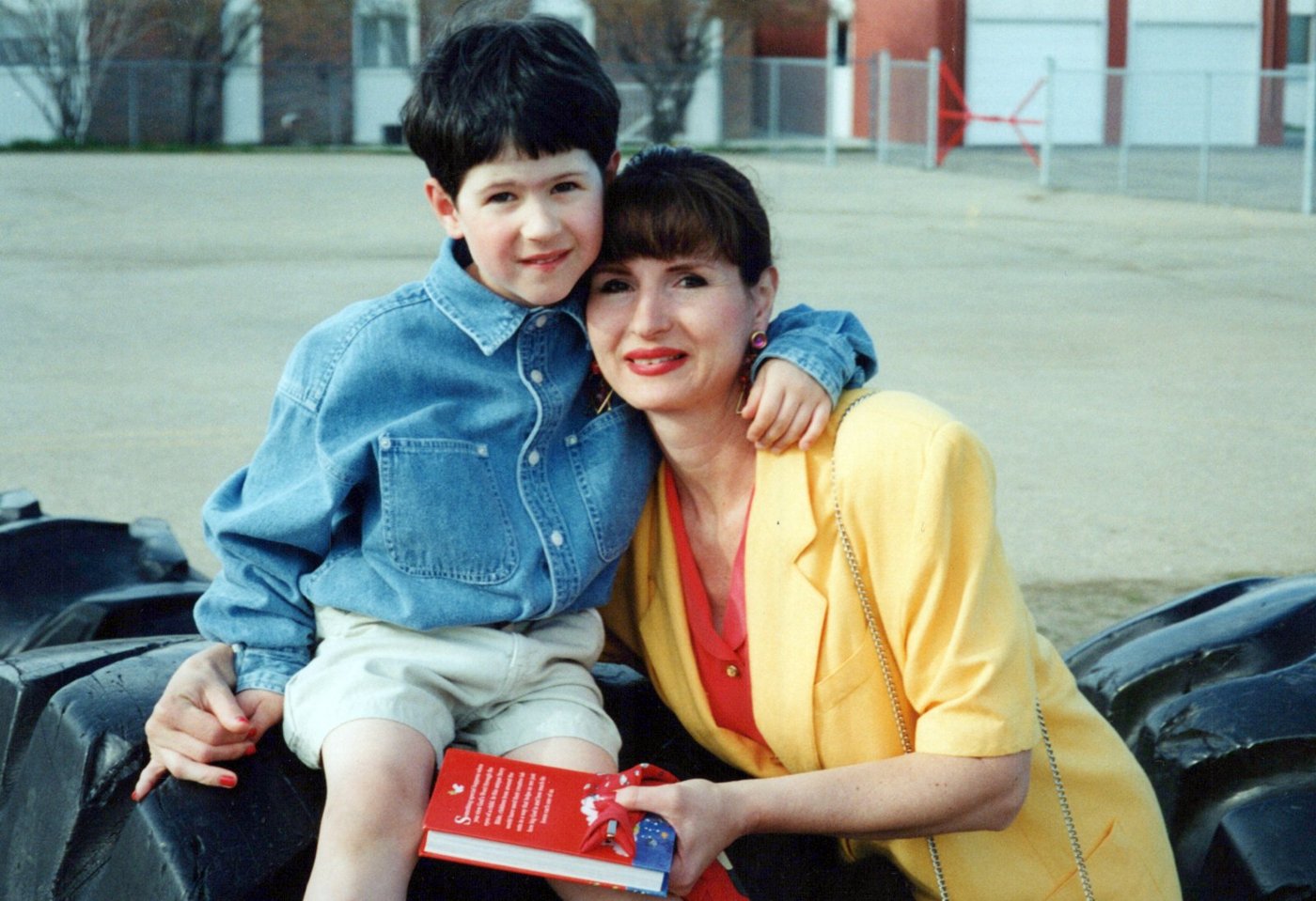 Drew as a young boy in a denim shirt, hugging his mom